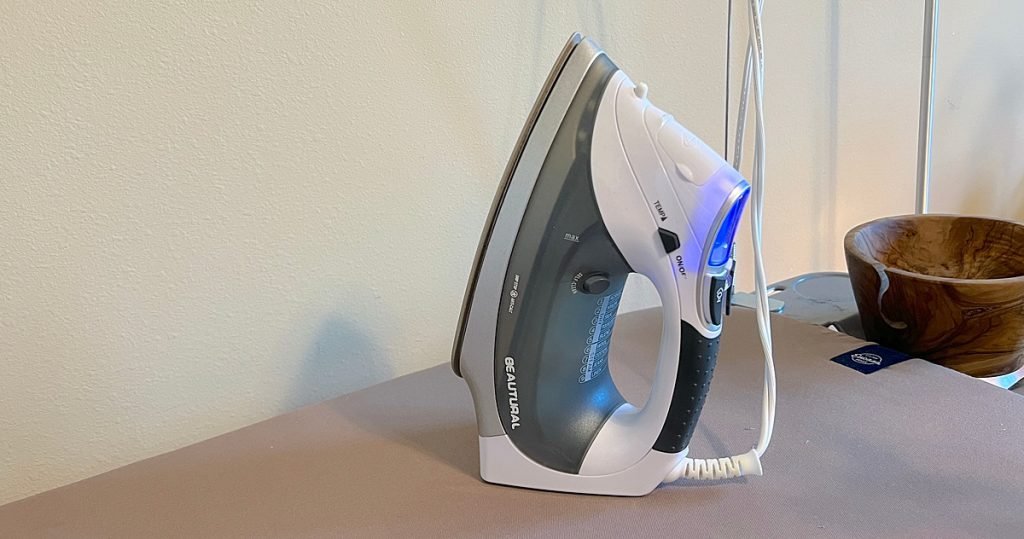 A steam iron standing on an ironing board